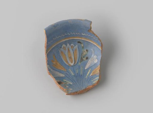 Fragment of red-fired earthenware, with a foot ring, glazed blue on the front, with a bouquet of flowers in yellow, white, blue, green and orange, stripes around it and a wavy rim