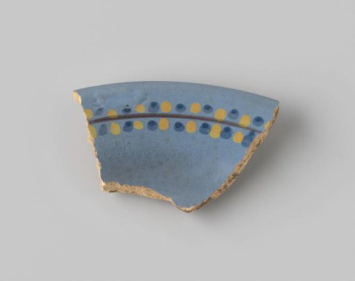 Fragment of yellowish-fired earthenware, glazed blue on the front, with a black stripe and blue and yellow dots on either side