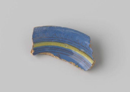 Fragment of reddish-fired earthenware, glazed blue on the front, with stripes and a wavy rim in yellow and black