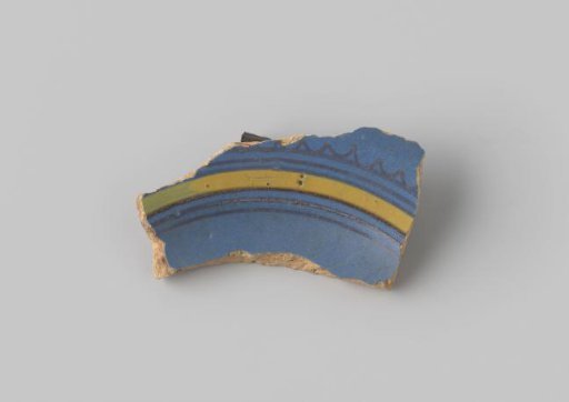 Fragment of reddish-fired earthenware, glazed blue on the front, with stripes and wavy lines in brown and yellow