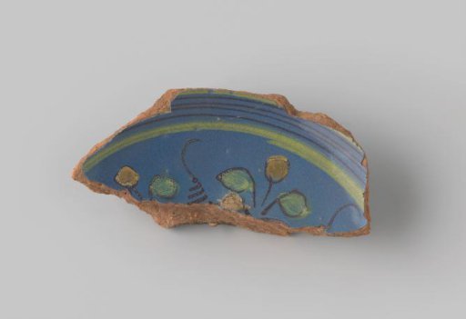 Fragment of red-fired earthenware, glazed blue on the front, with a painting of leaves in green and orange and stripes in yellow and brown