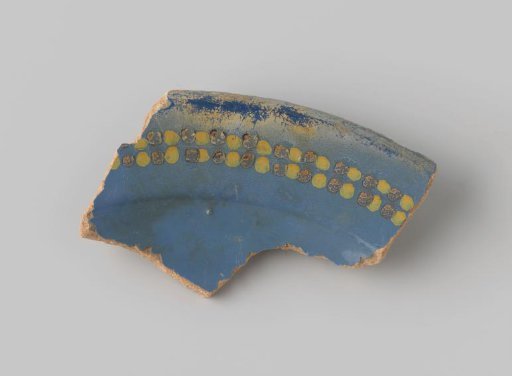 Fragment of reddish-fired earthenware, glazed blue on the front, with yellow and orange dots on either side of a stripe