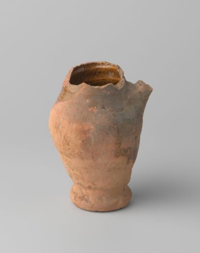 Pitcher of red-baked earthenware, glazed on the inside and partly on the outside, with damaged rim, foot and handle