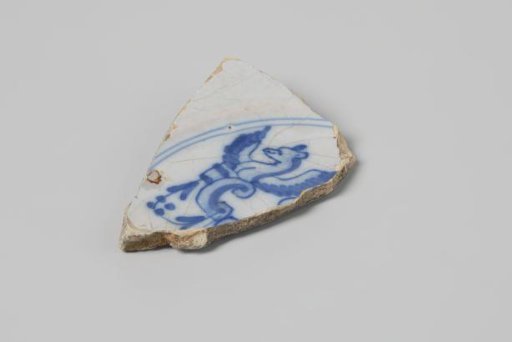 Sherd of a plate of earthenware with white tin glaze on the underside and white tin glaze on the upper side and a winged animal in blue, damaged