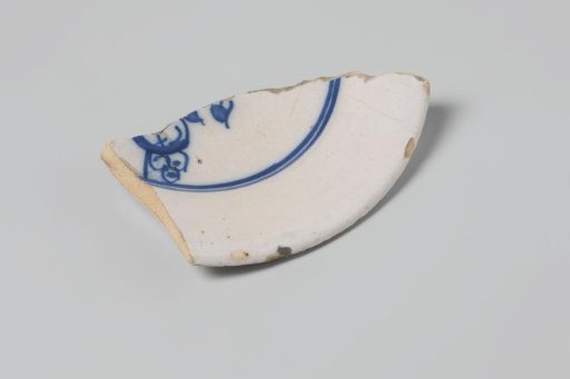 Sherd of a plate of earthenware with white tin glaze on the underside and white tin glaze on the upper side and a decoration in blue, damaged