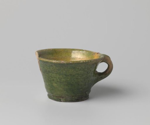 Cup with handle, of white-firing clay, glazed yellow on the inside and green on the outside, damaged
