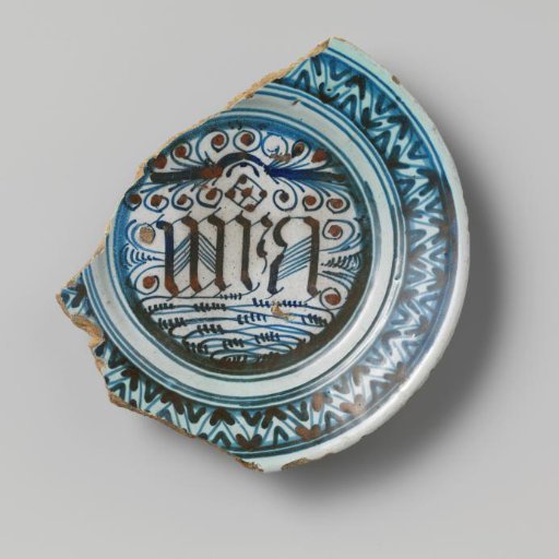 Earthenware plate, glazed with lead glaze on the underside and tin glaze on the upper side, and in blue, among other things, the letters omega M A, damaged
