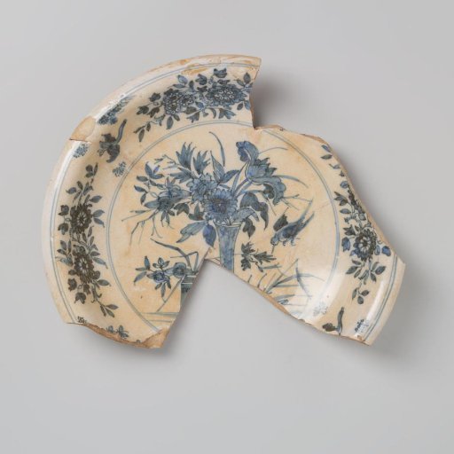 Plate shard of earthenware, glazed white on the top and bottom sides, with a blue floral design on the top side, damaged