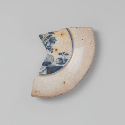 Plate shard of earthenware, glazed white on the top and bottom sides, with a blue design of flowers and fruit on the top side, damaged