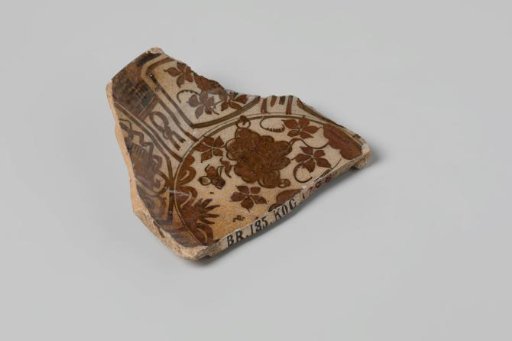 Plate shard of earthenware, glazed on the top and bottom sides, with a blue floral decoration on the top side, damaged