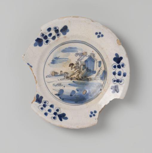 Plate shard of earthenware, glazed white on the top side and lead-glazed on the bottom side, with a blue landscape with a floral border on the top side, damaged