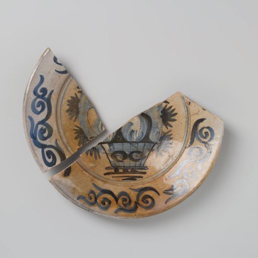Earthenware dish, glazed with lead glaze on the underside and white tinglaze on the upper side, with a fruit basket in blue among other things, damaged
