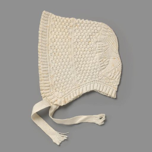 Knitted cap of white cotton with a pleated border, largely decorated with a piqué pattern between openwork borders and with a star motif at the back; two ribbon ties