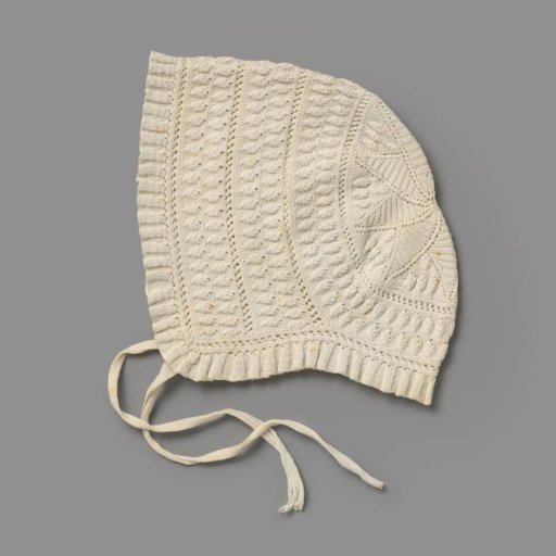 Knitted cap of white cotton with a pleated border all around and with two ribbon ties; decorated with leaf borders and openwork borders and with a star motif at the back
