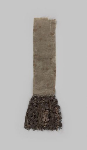 Fringe of silver thread decorated with three garlands with loops alternating with cartouches in the form of four-leaf rosettes, at the end a silk taffeta ribbon