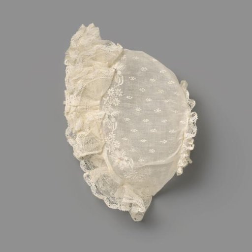 Children's cap of white batiste (?) with white embroidery with scatter motif and floral and leafy vines, trimmed around with ruche of tulle and lace; trimmed at the back with lace