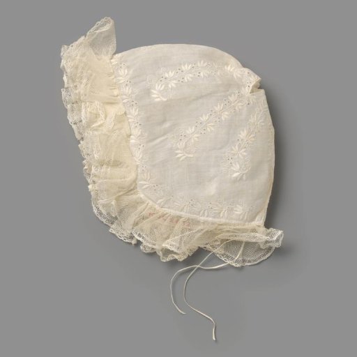 Children's cap of white batiste with an openwork floral motif on top, with spreading white embroidered leafy vines and with a leafy vine around and gathered tulle ruche and lace