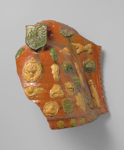 Fragment of a fire pot with a handle; on the wall in relief lion, angel, and human heads