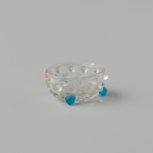 Bowl of clear colourless glass decorated with warts or knobs, standing on three blue ball feet.