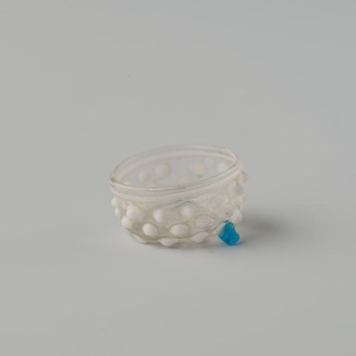 Bowl of clear colourless glass decorated with white knobs and white wire around the rim, standing on (originally) three ball feet. Two ball feet are missing.
