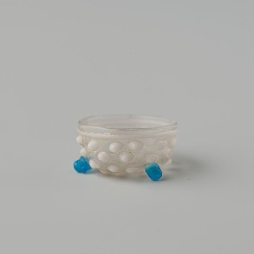 Bowl of clear colourless glass decorated with white knobs and white wire around the rim, standing on (originally) three ball feet. Two ball feet are missing.