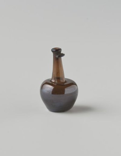 Bottle of clear brown glass; body with impressed eyes, high neck with drip ring (mostly broken), cork in neck opening.