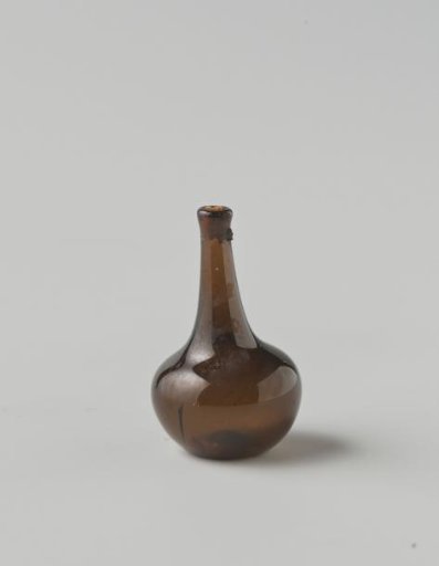 Bottle of clear brown glass; body with impressed eyes, high neck with drip ring (mostly broken), cork in neck opening.