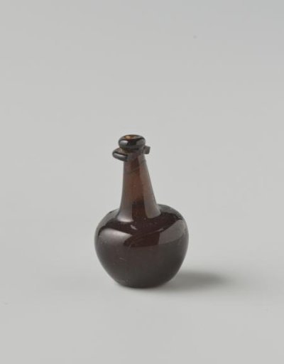 Bottle of clear brown glass; body with impressed eyes, high neck with drip ring (mostly broken), cork in neck opening.