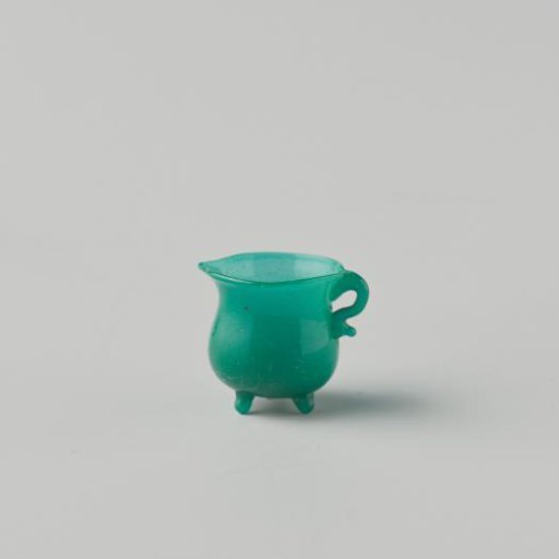 Cooking jug of opaque green glass (probably imitation green earthenware); on three feet, with spout and handle.