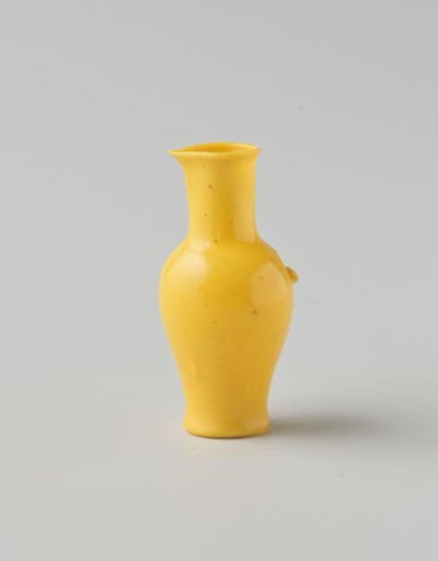 Jug of opaque yellow glass (probably imitation yellow earthenware); round and slender model with spout, applied handle and indented base.