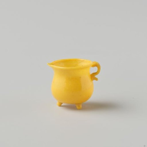 Cooking jug of opaque yellow glass (probably imitation yellow earthenware); on three feet with spout and handle.