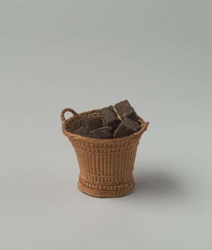 Round high peat basket of split willow, fine wickerwork, with two handles; filled with blocks of peat.