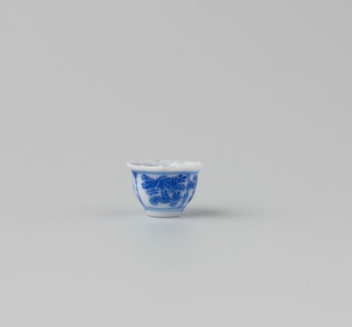Milk-glass teacup with blue enamel painting, imitation Chinese porcelain with 'flower' decoration in three compartments; model with a pointed rim, barely a foot ring.