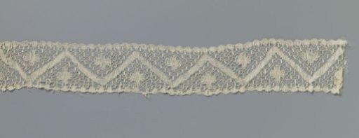 Bobbin lace strip with four-lobed rosette above and below a zigzag band