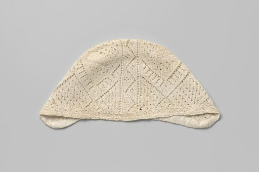 Knitted cap of white cotton with open circles, zigzag borders and an openwork border across the middle