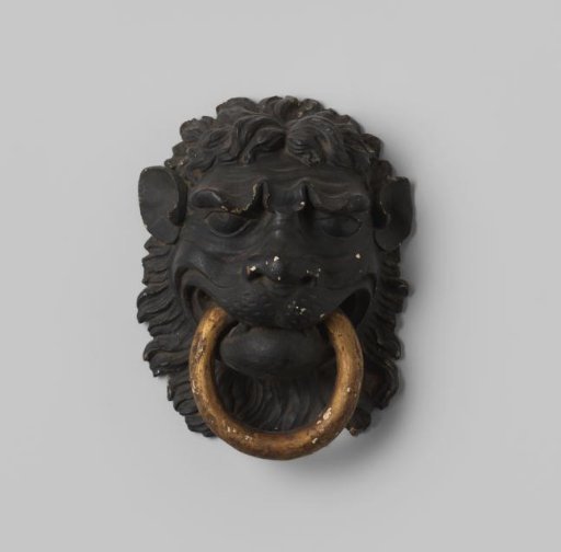 Door knocker in the form of a lion's head of wood with a gilded ring in its mouth