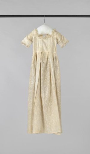 A white batiste baptismal gown, decorated with fine chain-stitch embroidered rinceaux, lined with white silk, the neckline and sleeves trimmed with fine linen lace, and a batiste collar edged with lace.