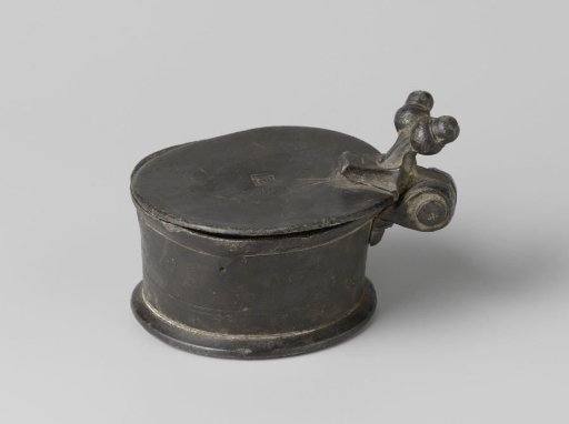 Tin salt cellar with a pilgrim's badge on the bottom
