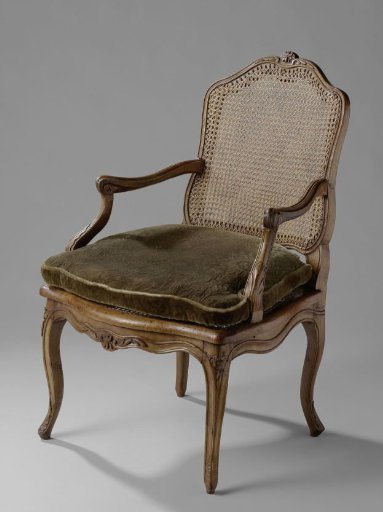 Armchair with a cane seat and back and a loose cushion. Diagonally placed S-shaped legs and a shaped lower stretcher.