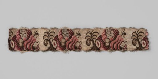 Sash of silk brocade; on a silver-colored ground is a repeating pattern in dark red, pink and brown in the form of a snail shell (?) from which fruits and leaves emerge