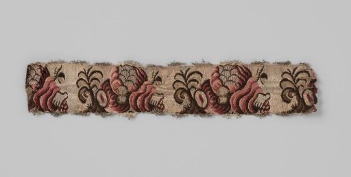 Sash of silk brocade; on a silver-colored ground is a repeating pattern in dark red, pink and brown in the form of a snail shell (?) from which fruits and leaves emerge