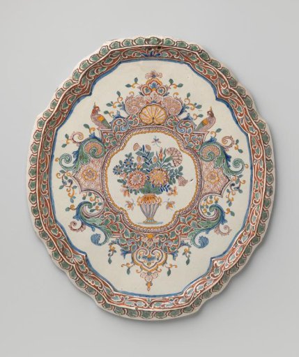 Plate, oval with scalloped edge, multicolored painted with a medallion containing a flower vase between lambrequins
