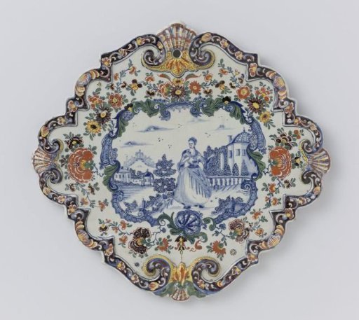 Plate, diamond-shaped with scalloped edge. Within multicoloured border a scene in blue painted of a lady in a garden