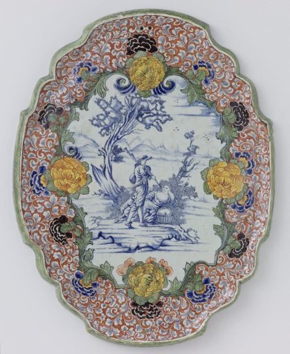 Plate, oval with scalloped edge, with shepherd scene in blue, framed by a multicoloured flower border
