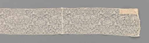 Strip of bobbin lace with X-shapes made of narrow decorative bands with rectangular motifs