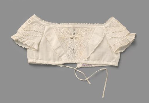 Bodice of a white cotton children's dress, with trapezium-shaped front with floral and leafy scrolls of English embroidery; finished with scalloped festooned edges and ruffles