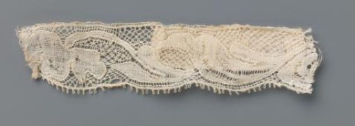 Strip of bobbin lace with an incomplete pattern of a flower and two leaves