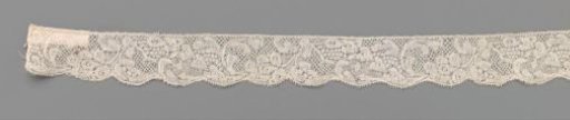 Strip of bobbin lace with heart-shaped leaves flowing into a flower stem