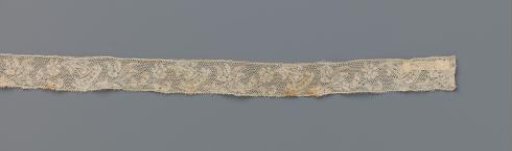 Strip of bobbin lace with wavy line of three different flowers