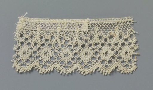 Strip of bobbin lace with a row of small circles under a row of trefoils